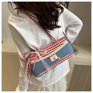 Detail of blue denim shoulder bag with red plaid trim, lace edges and cherry embroidery