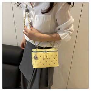 Detail of yellow quilted leather chain bag featuring camellia charm and silver accents