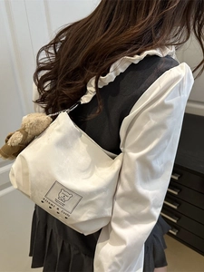 White canvas tote bag with ruffled shoulder strap and a cute plush bear charm