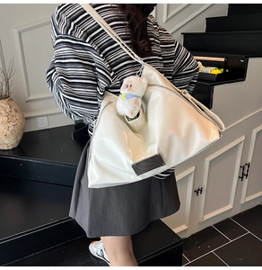 Detailed view of white high-gloss tote bag with silver plaque and plush bear pendant