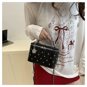 Detail of black quilted chain bag with silver studs and a rose flower charm