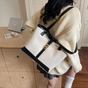 Contrast leather tote bag with gold buckle shown on desk in modern office setting