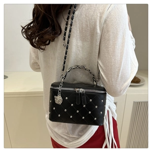Detail of black quilted leather box bag with silver camellia charm and chain strap