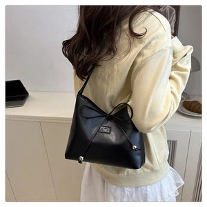 Detail der schwarzen Umhängetasche aus Leder mit großer Schleife und metallischen Perlen
