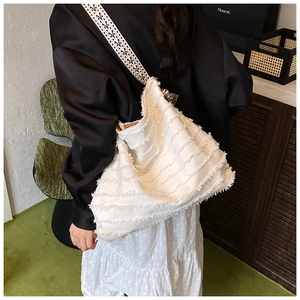 Detail der weißen Canvas-Tasche mit Fransenakzenten und geometrischem Webgurt