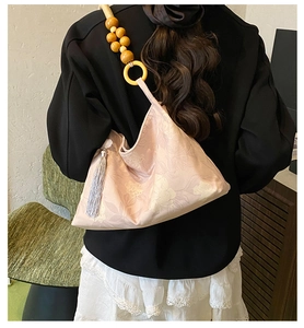 Détail du sac bandoulière en satin fleuri rose avec bandoulière unique en grosses perles de bois