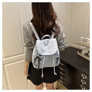 Close-up of light blue nylon backpack featuring Nika embroidery and black ribbon bow details