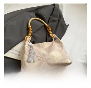 Détail du sac seau floral avec poignée en perles de bois et pompon argenté