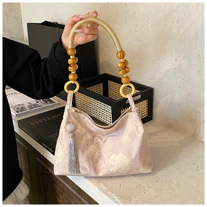 Detail of pink floral canvas bag featuring braided handles and gray tassel pendant