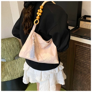 Dettaglio borsa jacquard floreale rosa con manico in perline di legno e nappa sulla spalla