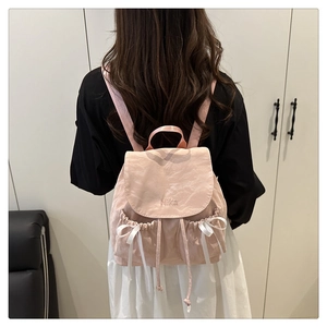 Close-up of pink backpack featuring Nika embroidery and white ribbon bow detail