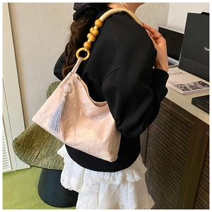 Détail du sac à bandoulière en jacquard rose avec bandoulière en perles de bois et gland
