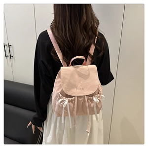 Détail du sac à dos rose en nylon avec broderie Nika et nœuds en ruban de soie blanc
