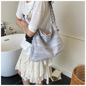 Détail du sac cabas en toile bleu clair avec franges et bandoulière à motif géométrique