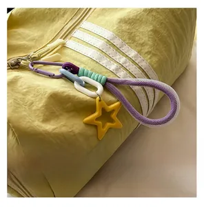 Close-up of yellow pleated crossbody bag featuring iconic side stripes and a star keychain