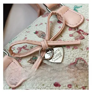Macro detail of textured Boston bag with heart charm and pink leather bow accent