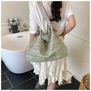 Détail du grand sac cabas en paille avec texture à franges et bandoulière géométrique
