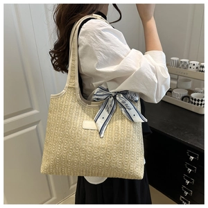 Detail of woven straw tote bag with printed Paris scarf handle and leather logo patch