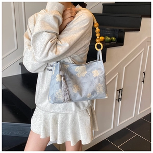 Détail du sac à fleurs bleu clair avec bandoulière en perles de bois et gland