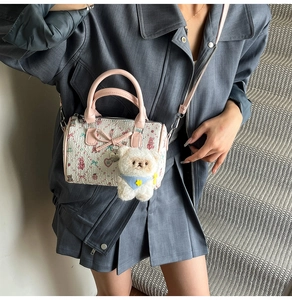 Detail of mini canvas Boston bag featuring pink bear patterns, bow, and plush charm