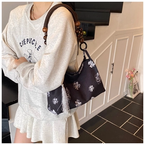 Detail of black canvas tote with white floral print and dark brown wooden bead handles