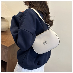 Close-up of cream white crescent shoulder bag featuring a silver metal bow detail