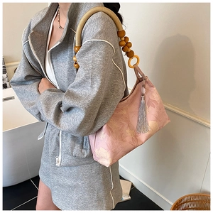 Dettaglio della borsa tote rosa a fiori con tracolla etnica intrecciata e nappa