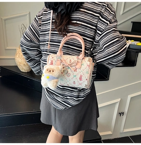 Detail of cream Boston bag with pink bear prints and a cute plush bear charm accessory