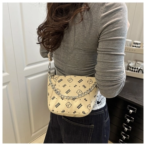 Detail of luxury beige bucket bag with bear print pattern and silver chain strap