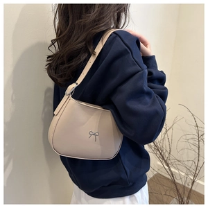 Close-up of a cream crescent underarm bag featuring a silver metal bow buckle detail