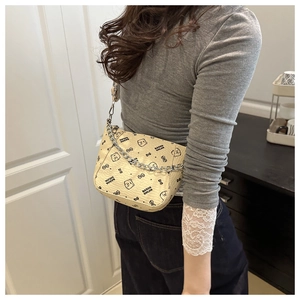 Detail van beige monogram emmer-tas met berenprints en een gouden schakelketting riem