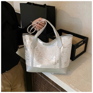 Détail de la texture florale argentée métallisée et du logo sur le sac cabas avec bandoulière
