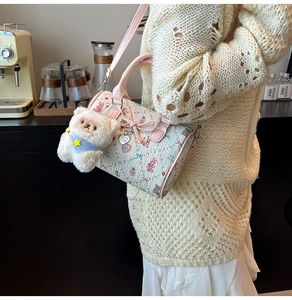 Detail of floral Boston bag with pink bow, heart charm and plush bear accessory
