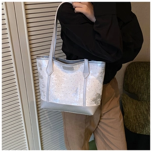 Détail d'un sac cabas en toile brodé avec motifs papillon et finitions argentées