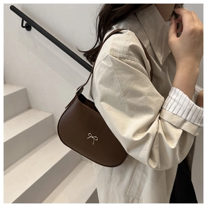 Close-up of dark brown leather underarm bag featuring a silver bow metal decoration
