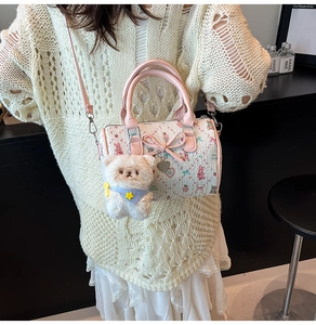 Close-up of cream Boston bag with pink leather trim and cute plush bear charm