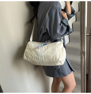 Detailed side view of white cylindrical tote bag with three stripes on casual shoulder strap