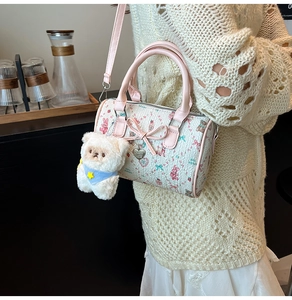 Detail of Boston bag featuring pink bow accents and a plush bear pendant with heart charm
