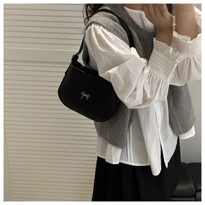 Detail of black matte leather hobo bag with a delicate silver bow charm accessory