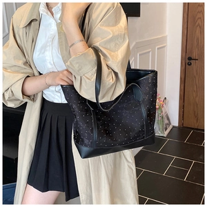 Close-up of black polka dot tote bag with premium leather straps and velvet fabric texture