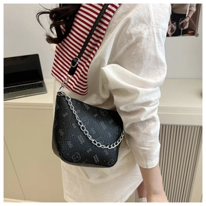 Detail of black pebbled leather bucket bag featuring a white bear print and silver chain