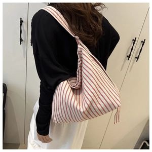 Detail view of large red striped canvas tote bag with wide shoulder strap on model