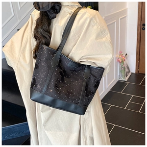 Détail du cabas noir brodé de papillons avec étiquette mode et rivets blancs
