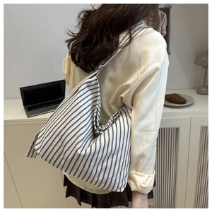 Détail du sac hobo en toile rayée montrant la texture épaisse et les anneaux en métal
