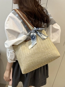 Woven straw tote bag with brown leather handles and a blue printed silk scarf detail