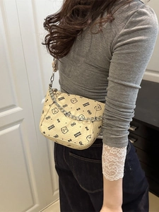 Beige emmertas met berenprint en metalen ketting, getoond door model in een interieur