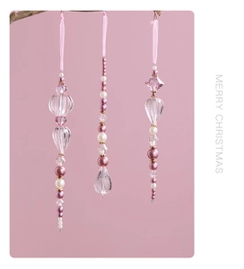 Detailed view of pink acrylic crystal Christmas ornaments hanging on a rustic branch