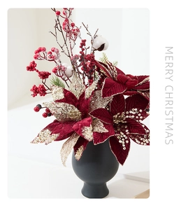 Close-up of velvet poinsettia and red berries in a matte black vase for Christmas decor