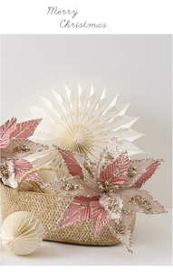 Detailed view of pink fabric Christmas flower with gold glitter edges in a woven basket
