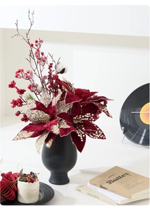Detailed Christmas floral arrangement with red poinsettias in a black ceramic vase